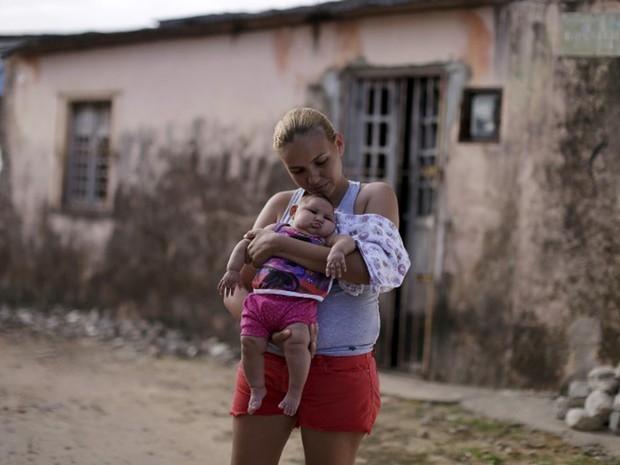 Gleyse da Silva segura a filha com microcefalia diante de sua casa, em Recife (Foto: Reuters/Ueslei Marcelino)
